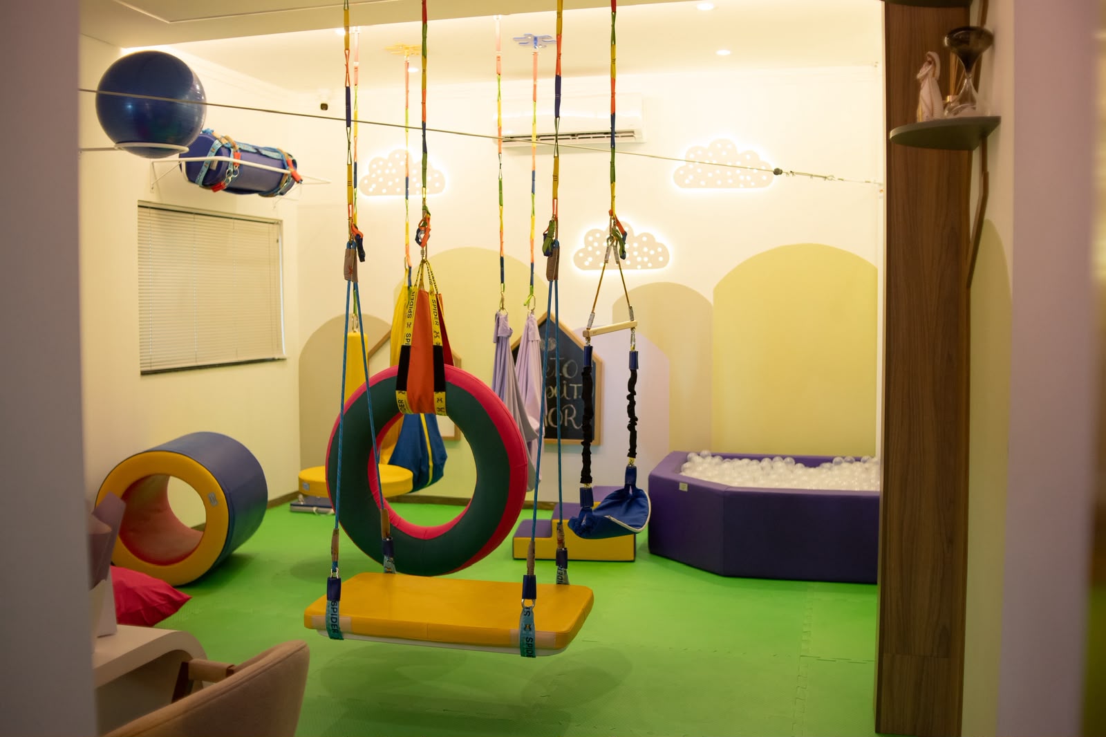 Sala de integração sensorial com balanços, piscina de bolinhas e obstáculos