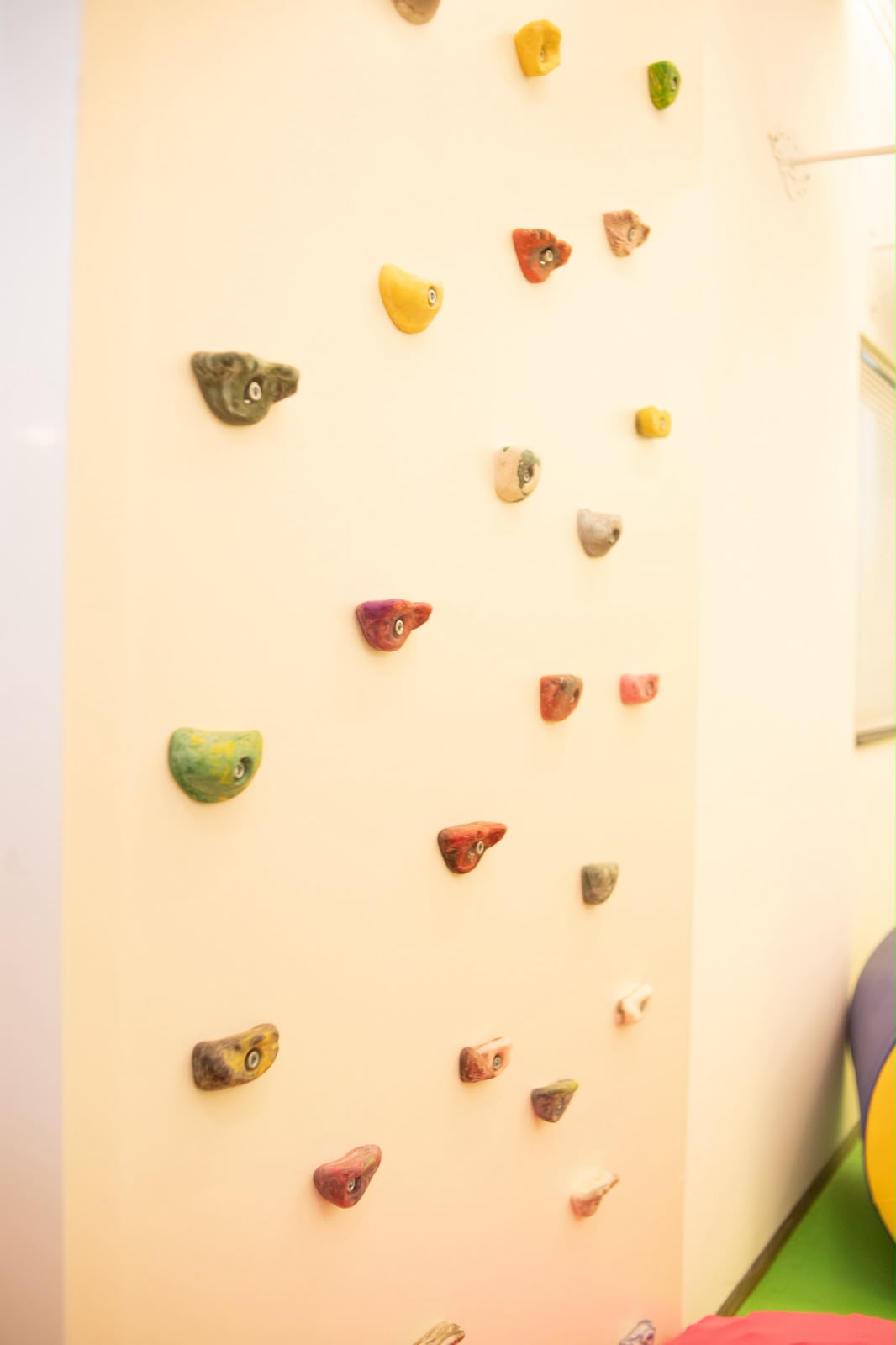 Parede de escalada infantil com apoios coloridos